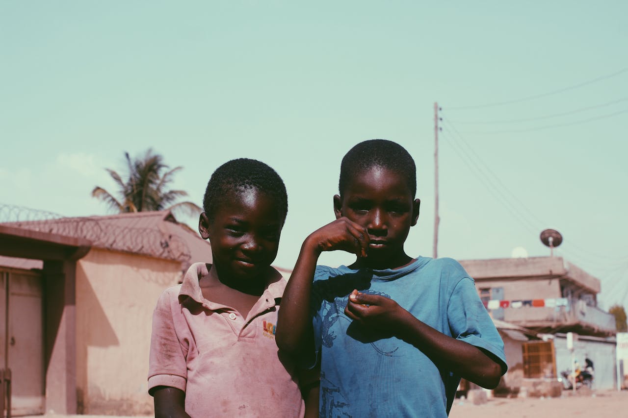 services-04 Two African boys smiling and posing outdoors, showcasing friendship in a rural setting.